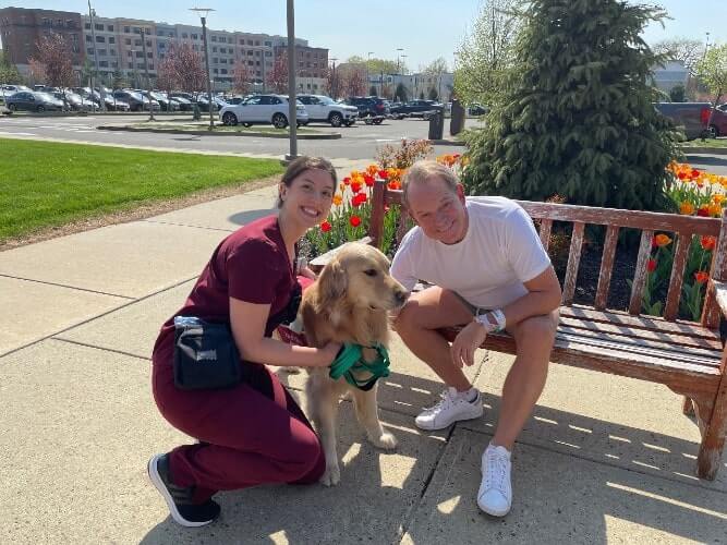 A nurse, dog, and patient posing for a picture