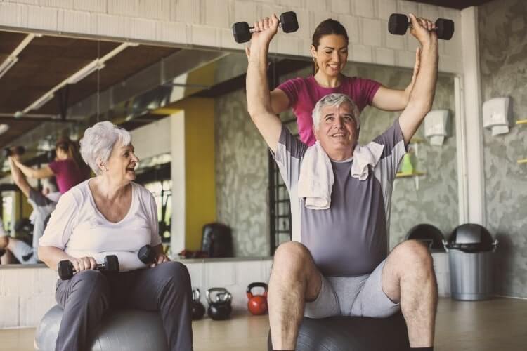 elderly couple working out with trainer