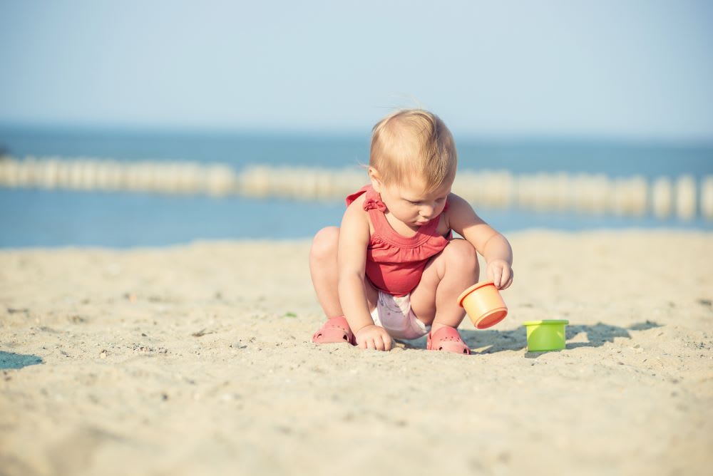 Baby sitting in sand at beach