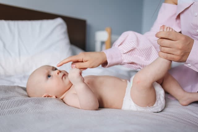 Baby on bed, playing with mother