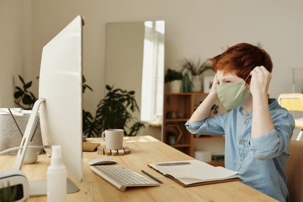 Boy wearing cloth mask in front of computer