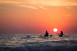 couple canoeing at sunset: tips to vacation mindfully