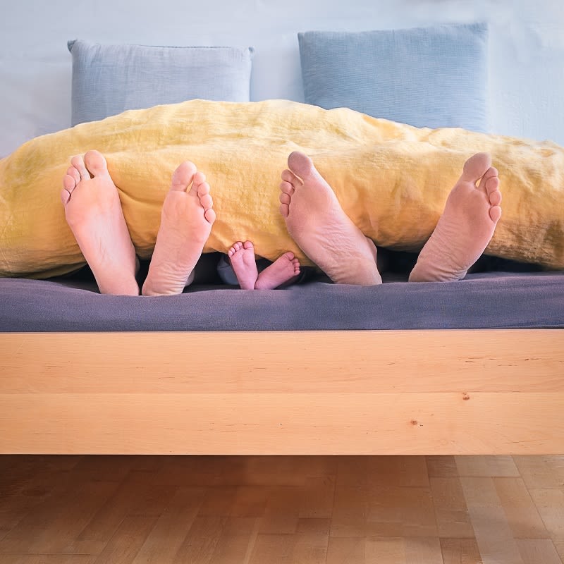 Mom, Dad and Baby Feet in Bed