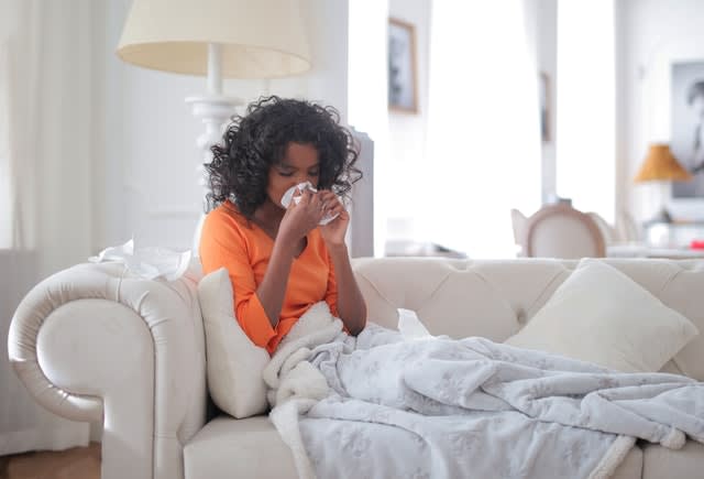 Sick woman on couch blowing nose